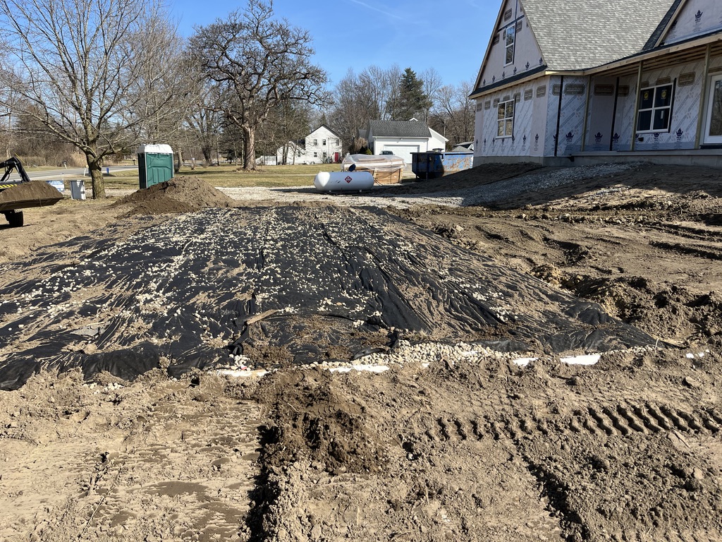 Septic drain field gravel bed installation with header pipe