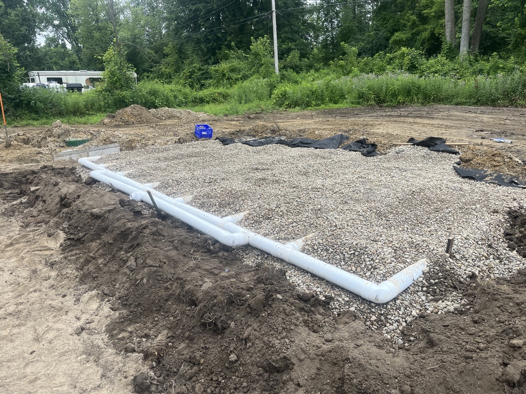 Septic drain field laterals being installed in a gravel bed